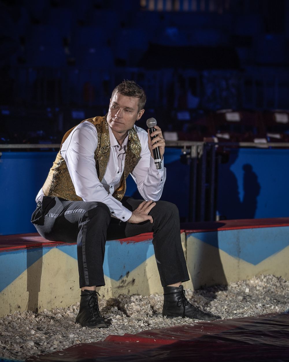 Jack Marsh sitting on the Circus Flora ring curb with a microphone